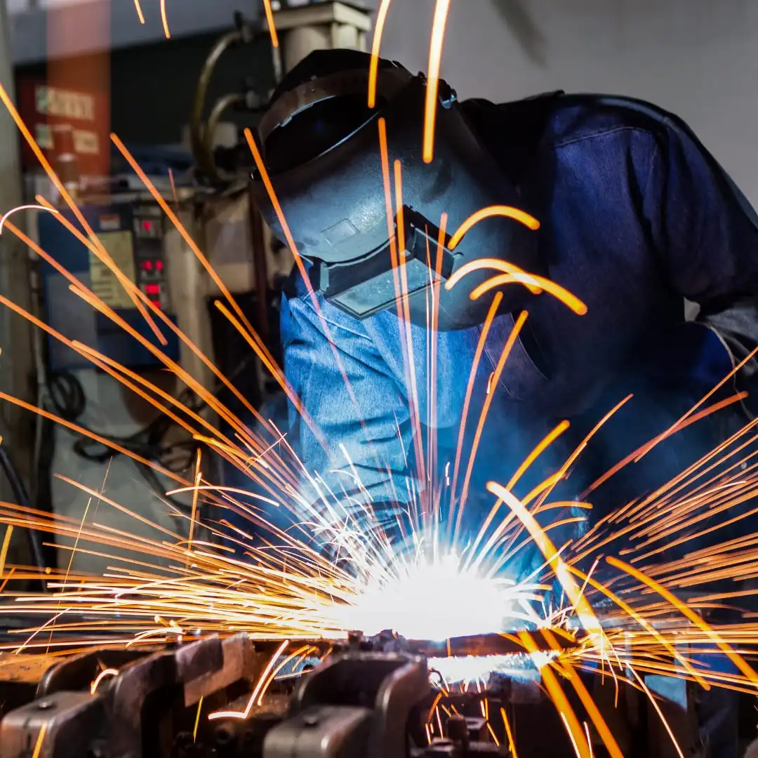 Soldador em operação com faíscas visíveis, representando os serviços de soldadura e maquinação de precisão da Victum.